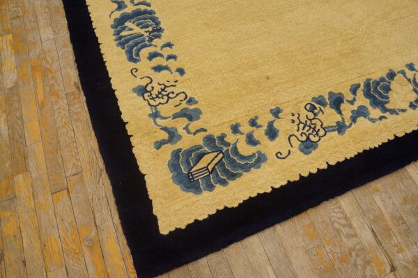 Gold pile rug with a navy border and blue scalloped design lies on worn wooden flooring.