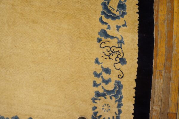 Plush yellow rug with blue stylized designs rests next to rustic orange wood flooring.