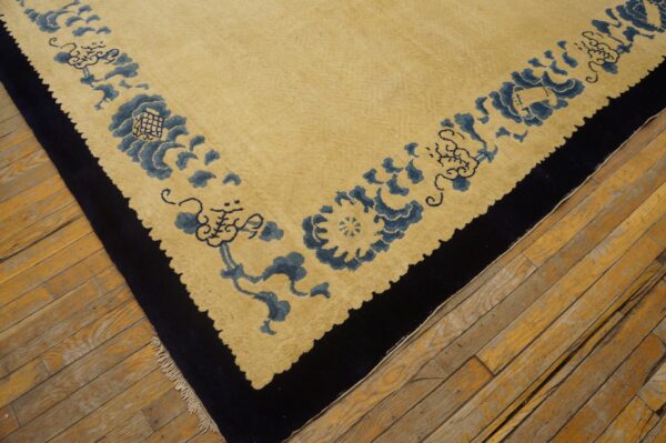 Yellow low-pile rug with a detailed blue floral border and dark outer edge on wooden flooring.
