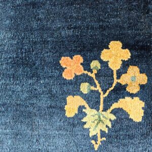 Dark blue high-pile rug detail with golden yellow and orange floral and green leaf pattern.