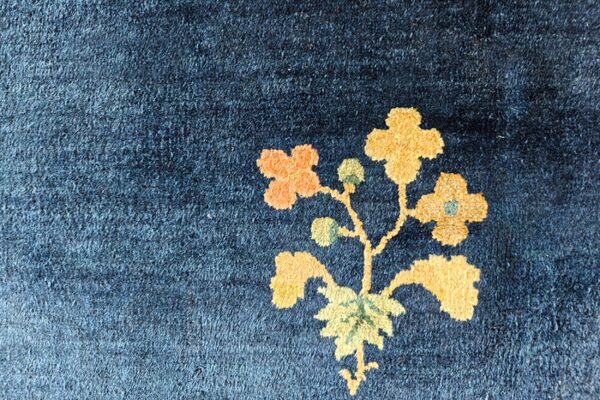 Dark blue high-pile rug detail with golden yellow and orange floral and green leaf pattern.
