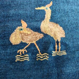 Textured, dark blue pile rug featuring a whimsical pattern of two light brown wading birds.