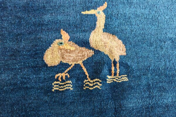 Textured, dark blue pile rug featuring a whimsical pattern of two light brown wading birds.