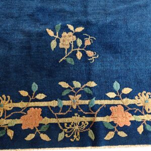 Deep navy blue rug featuring gold, peach, and green floral motifs and a detailed horizontal banded border.