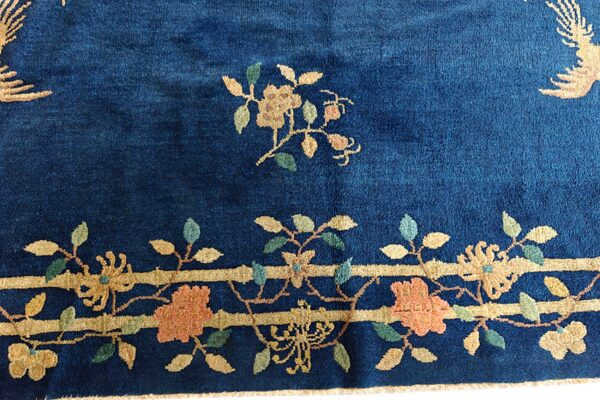 Deep navy blue rug featuring gold, peach, and green floral motifs and a detailed horizontal banded border.