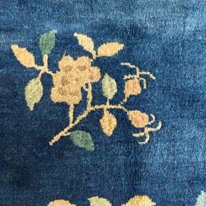 Close-up of a medium-pile navy blue rug with a beige and green floral stem motif.