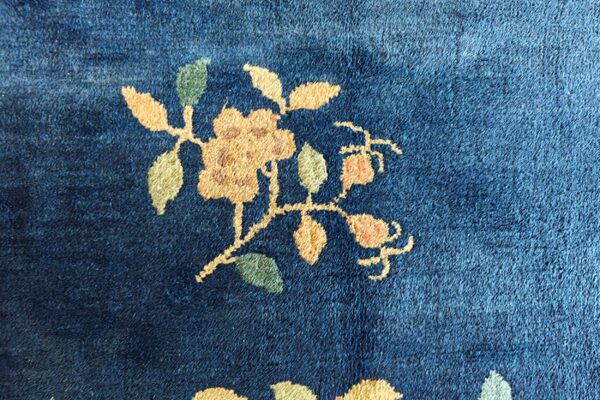 Close-up of a medium-pile navy blue rug with a beige and green floral stem motif.