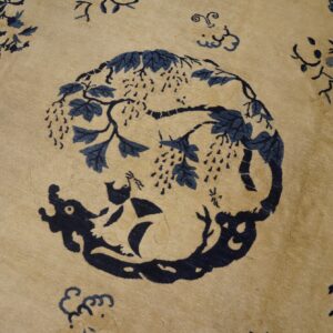 Tan rug with dark blue animal and vine motif surrounded by scattered light pink and blue floral elements.