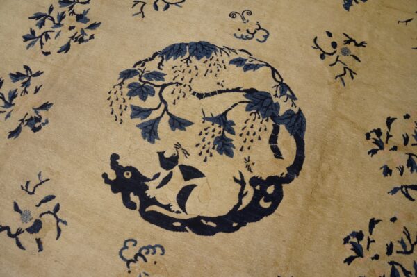 Tan rug with dark blue animal and vine motif surrounded by scattered light pink and blue floral elements.