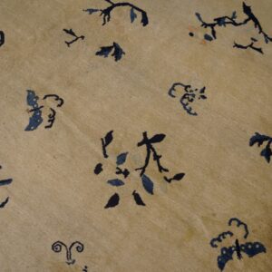 Beige rug field features scattered stylized dark blue and black floral and vine motifs.