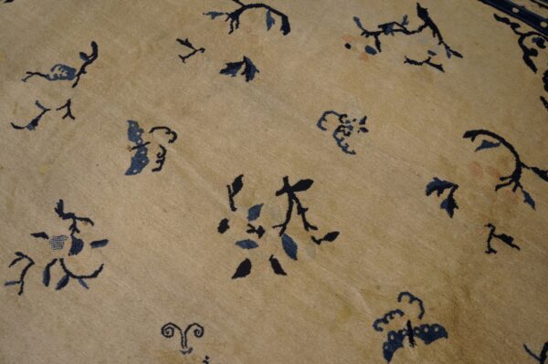 Beige rug field features scattered stylized dark blue and black floral and vine motifs.