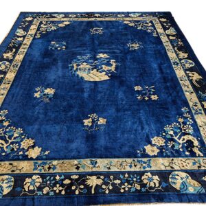 Deep blue rug featuring scattered tan florals, a central scenic medallion, and intricate bird-and-flower borders.