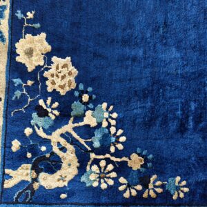 Deep blue rug detailed with cream and light blue floral blossoms along a decorative border.