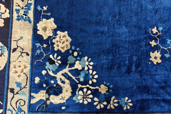 Deep blue rug detailed with cream and light blue floral blossoms along a decorative border.