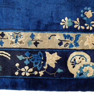 Velvety blue rug border with tan, light blue, and dark blue stylized floral and vine motifs.