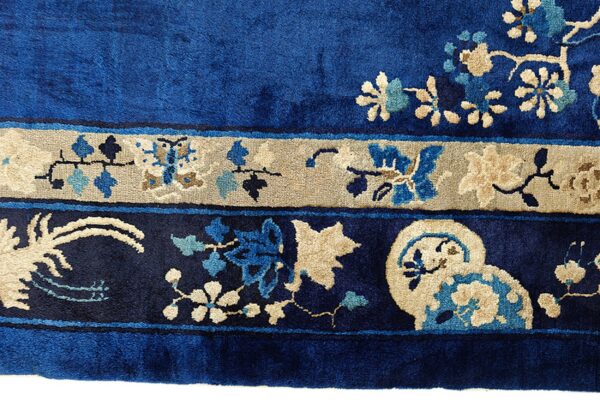 Velvety blue rug border with tan, light blue, and dark blue stylized floral and vine motifs.