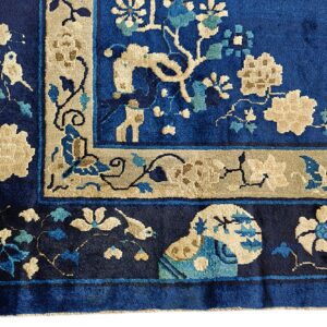 Deep royal blue rug corner with detailed beige and aqua floral motifs and wide decorative borders.
