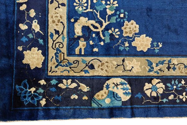 Deep royal blue rug corner with detailed beige and aqua floral motifs and wide decorative borders.