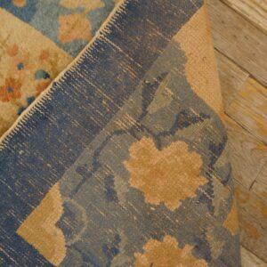 Floral blue rug, folded to expose its woven backing structure against distressed wooden planks.