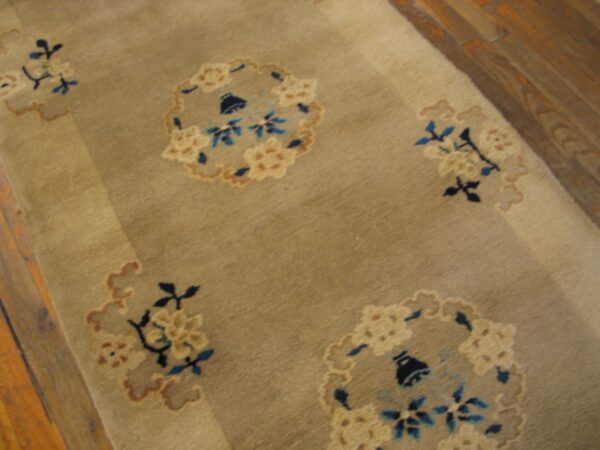 Muted beige rug runner with scattered blue and cream floral medallions visible on wood flooring.
