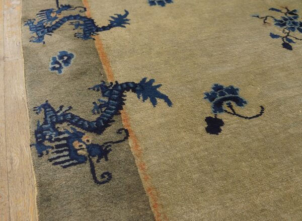 High-pile beige rug with dark blue dragon designs and rust accents beside wood planks.