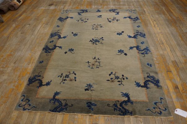 Light gray-green rug with scattered blue florals and a dark border featuring blue dragons rests on wood floorboards.