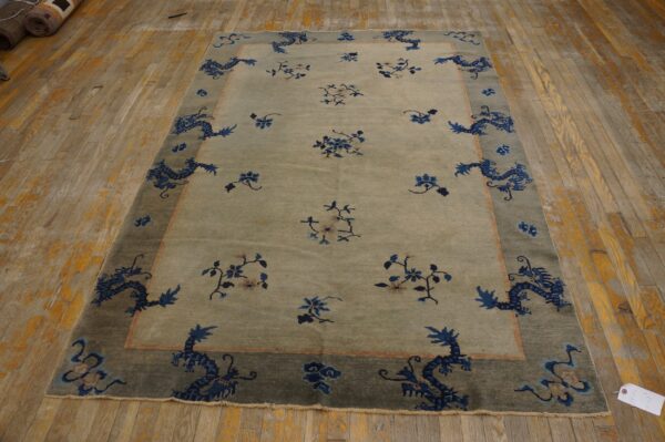 Pale green rug with a dark border features blue dragons and floral sprigs on distressed wood flooring.