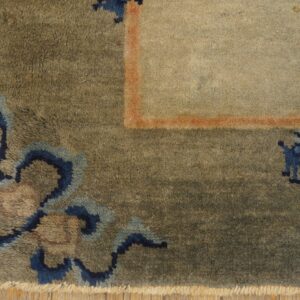 High-pile rug corner featuring blue patterns, an orange border line, a beige field, and wood flooring.