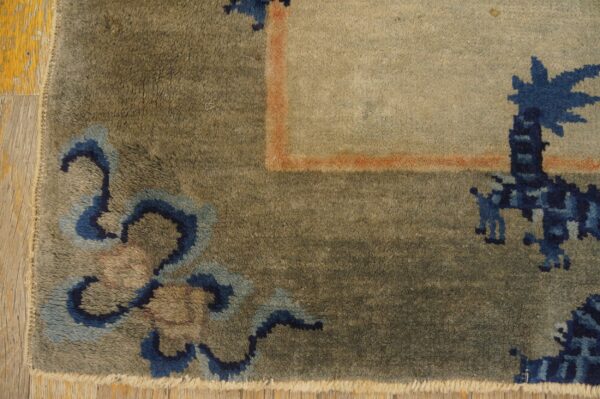 High-pile rug corner featuring blue patterns, an orange border line, a beige field, and wood flooring.
