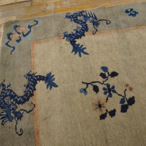 Textured gray rug featuring a detailed border with stylized blue dragons on rustic, light wood floorboards.