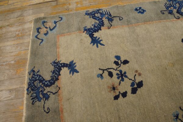 Textured gray rug featuring a detailed border with stylized blue dragons on rustic, light wood floorboards.