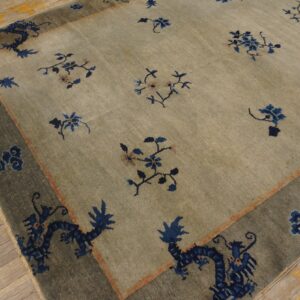 Sage-toned rug with blue floral and dragon patterns, displayed on wide, light-colored wooden floorboards.