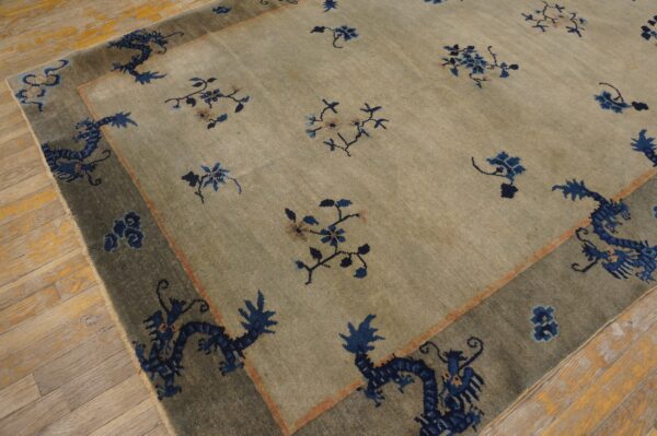 Sage-toned rug with blue floral and dragon patterns, displayed on wide, light-colored wooden floorboards.