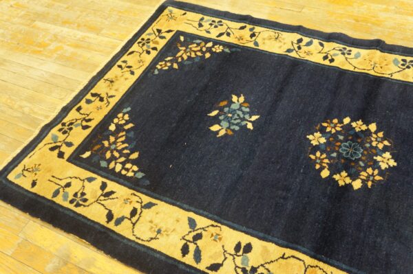 Navy blue rug featuring a golden yellow border with floral vine patterns on wooden planks.