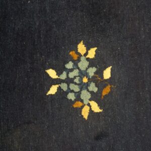 Close-up of dark blue rug pile featuring a floral motif in yellow, teal, and brown.