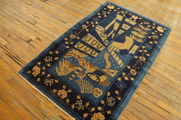 Blue and gold stylized rug with floral borders displayed on worn, yellow-toned wood flooring.