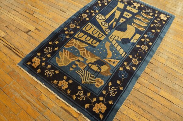Deep blue and gold abstract patterned rug with a dark floral border covers light wood floors.