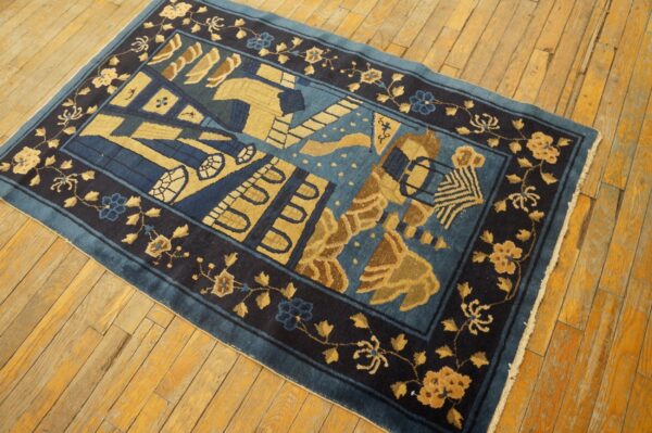Dark blue rug with a central abstract motif and gold floral borders resting on warm wooden floorboards.