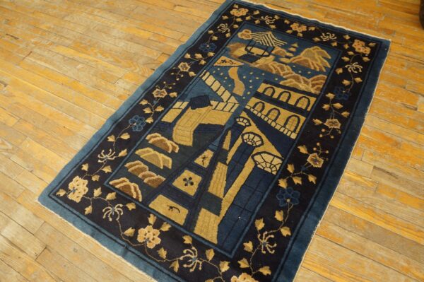 A dark blue and gold stylized rug featuring architectural patterns rests on rustic yellow wood plank flooring.