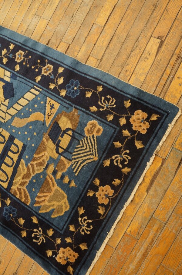 Blue and gold patterned rug with a deep navy floral border shown on rustic wood planks.