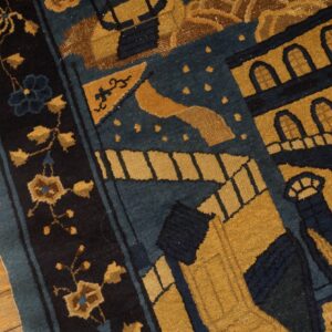 Blue and gold patterned rug displaying stylized buildings and florals next to worn hardwood flooring.