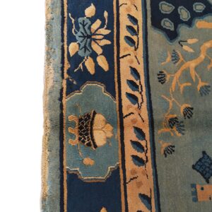 Low pile rug featuring navy blue, seafoam green, and tan ornate floral border patterns.