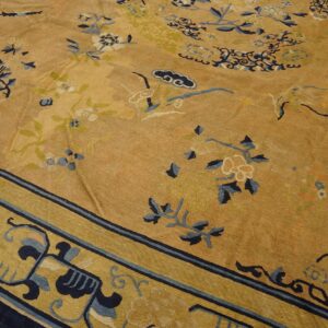 A textured gold rug with navy blue and green floral patterns rests on light wood flooring.