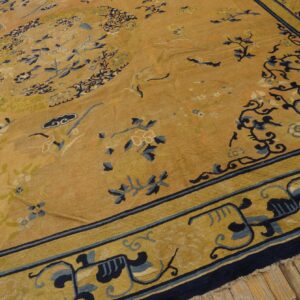 Traditional golden rug with dark blue and pale yellow botanical patterns rests on a wood floor.