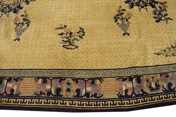 Tan rug with stylized floral motifs, a faint field pattern, and a wide blue and gold geometric border.