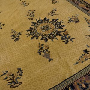Gold rug detailed with blue and pink floral designs, geometric borders, and set against light wood flooring.