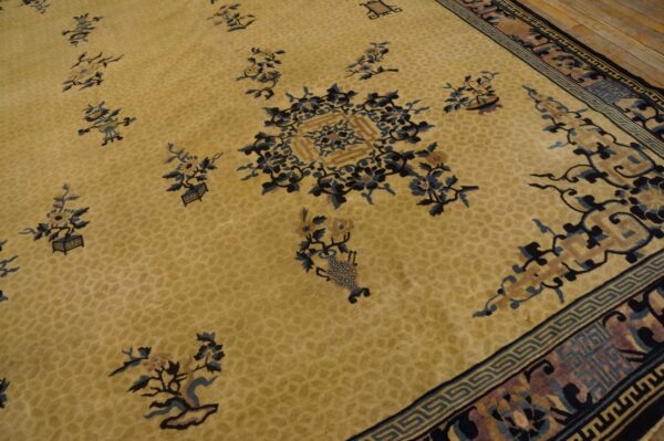 Gold rug detailed with blue and pink floral designs, geometric borders, and set against light wood flooring.