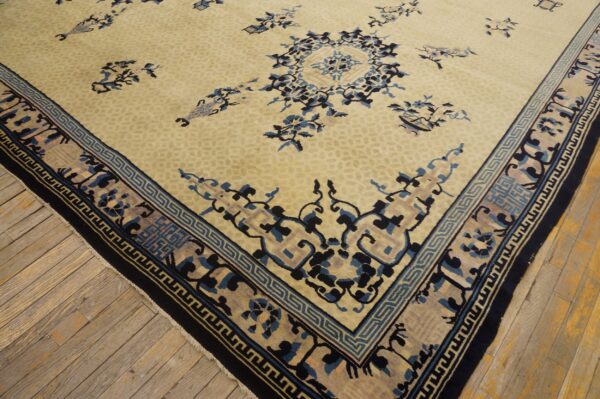 Pale yellow rug with scattered blue floral motifs and a detailed geometric border on light wood planks.