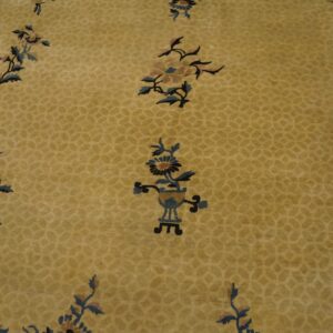 Low-pile golden rug with tone-on-tone geometric pattern and scattered dark blue botanical motifs.