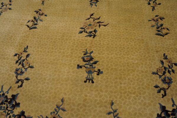 Low-pile golden rug with tone-on-tone geometric pattern and scattered dark blue botanical motifs.
